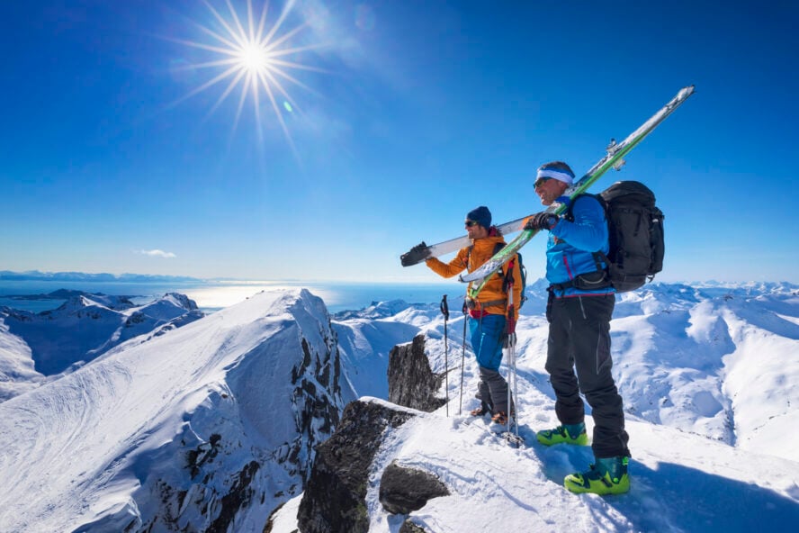 Ski tourers on a snowy peak in Lofoten, Norway getting ready for ski touring