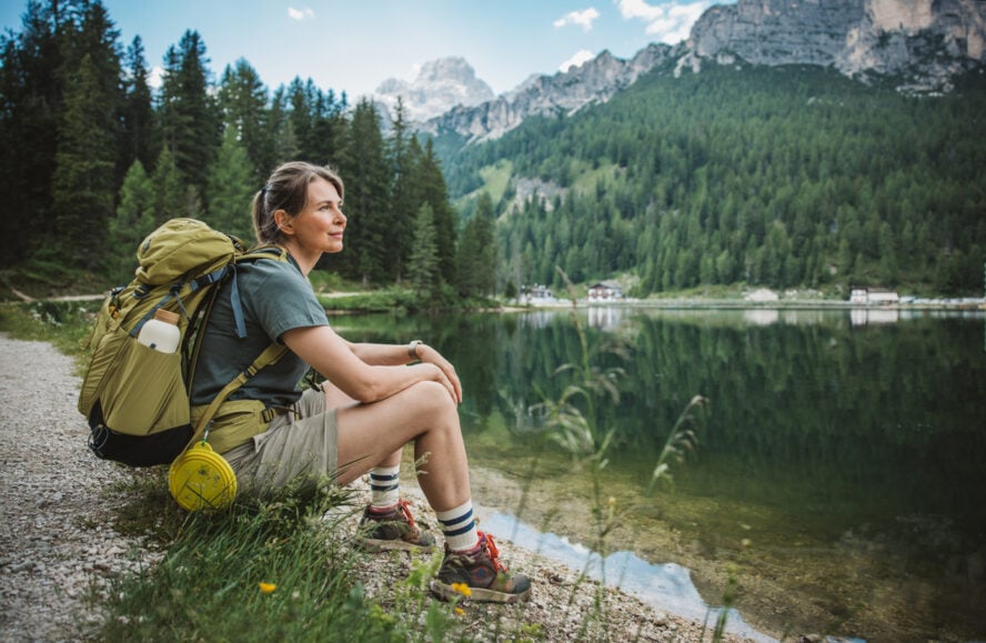 Portrait of woman sitting and looking at lake in Dolomites