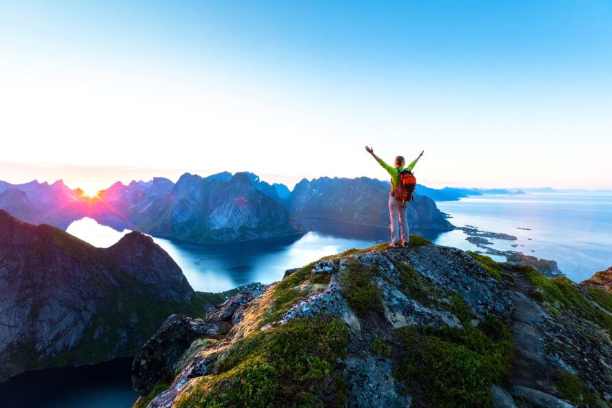 A happy hiker at sunset learning what a self-guided hike is in Lofoten, Norway