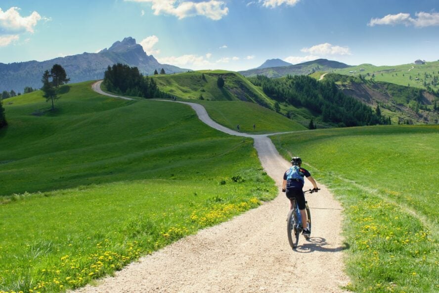 Cyclist on a meadow with the view of the Dolomites