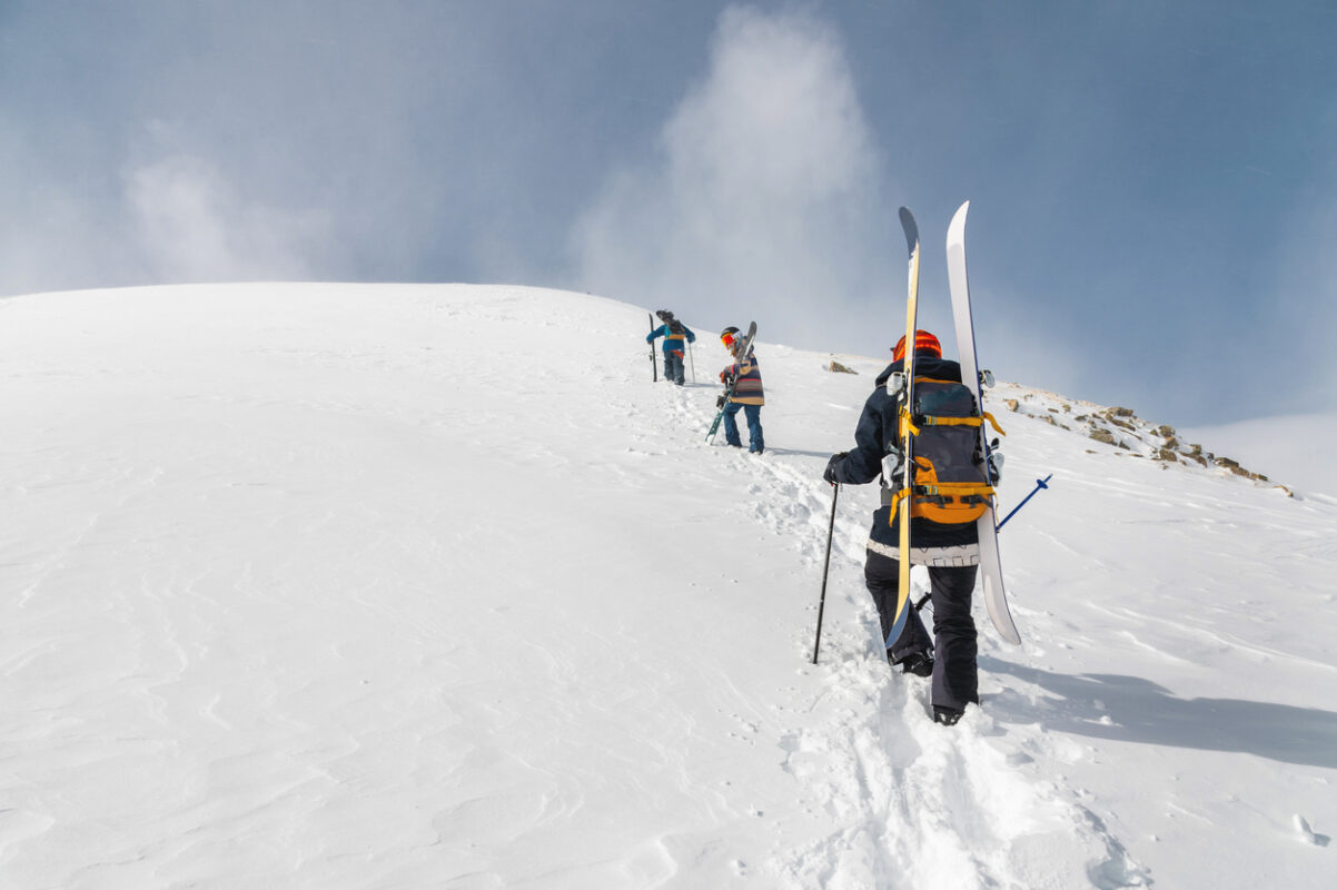 Skiers climbing a slope wearing their ski touring setup.