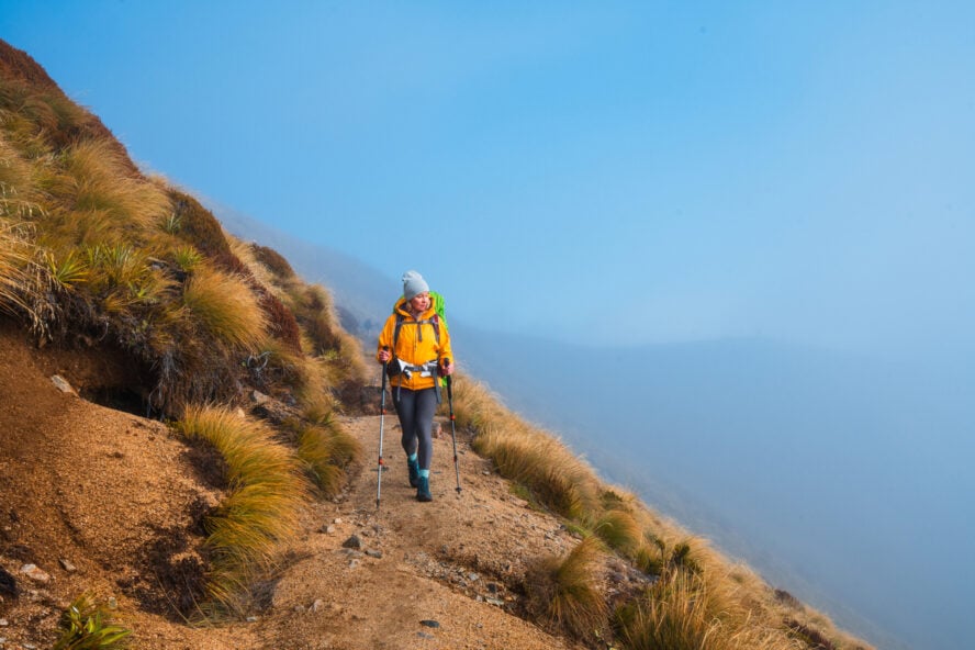 Female hiker on a mountain ridge hiking in equipment and poles.