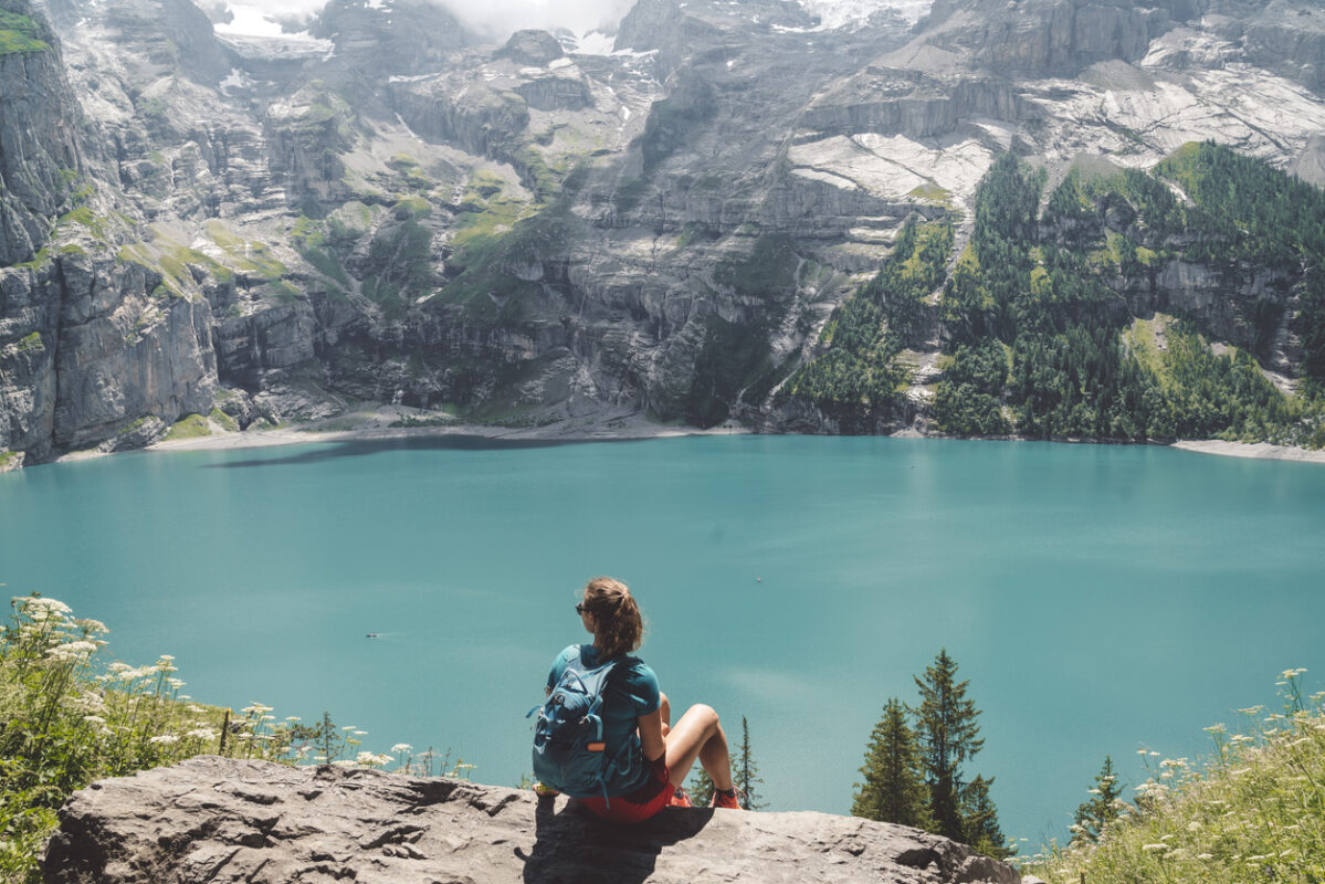 Woman hiker sitting at a viewpoint looking at Oeschinensee, Switzerland