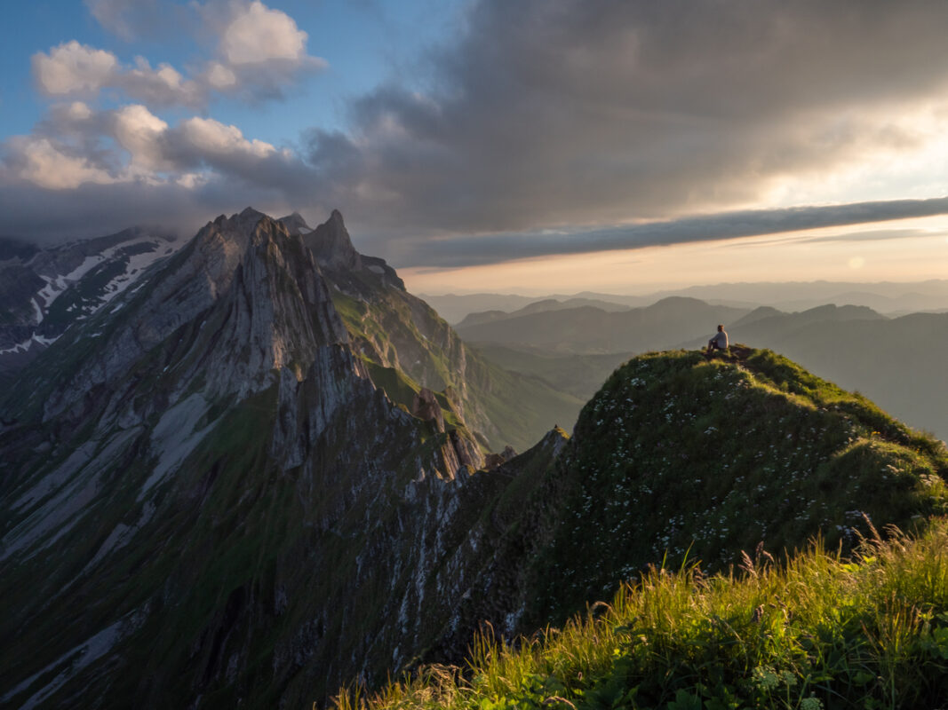 Rear view of man hiking on mountain ridge looking at spectacular view in Appenzellerland Canton, Switzerland