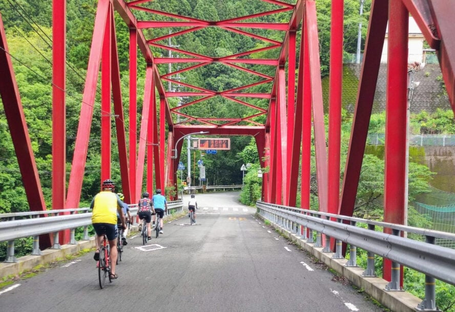 Cyclists on a red bridge in Japan