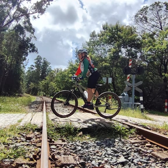Image 9: Cyclist crossing railway tracks on a wooded Camino trail