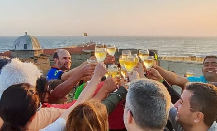 Image 8: Tour group raising glasses in a sunset toast by the Atlantic